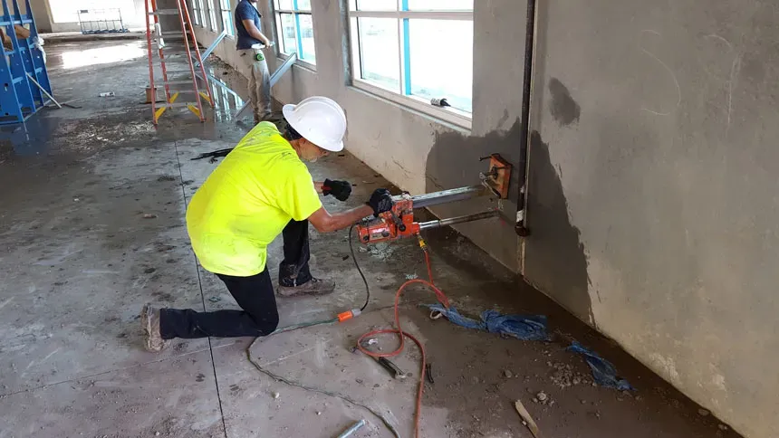 Technician drilling high on a reinforced concrete structure